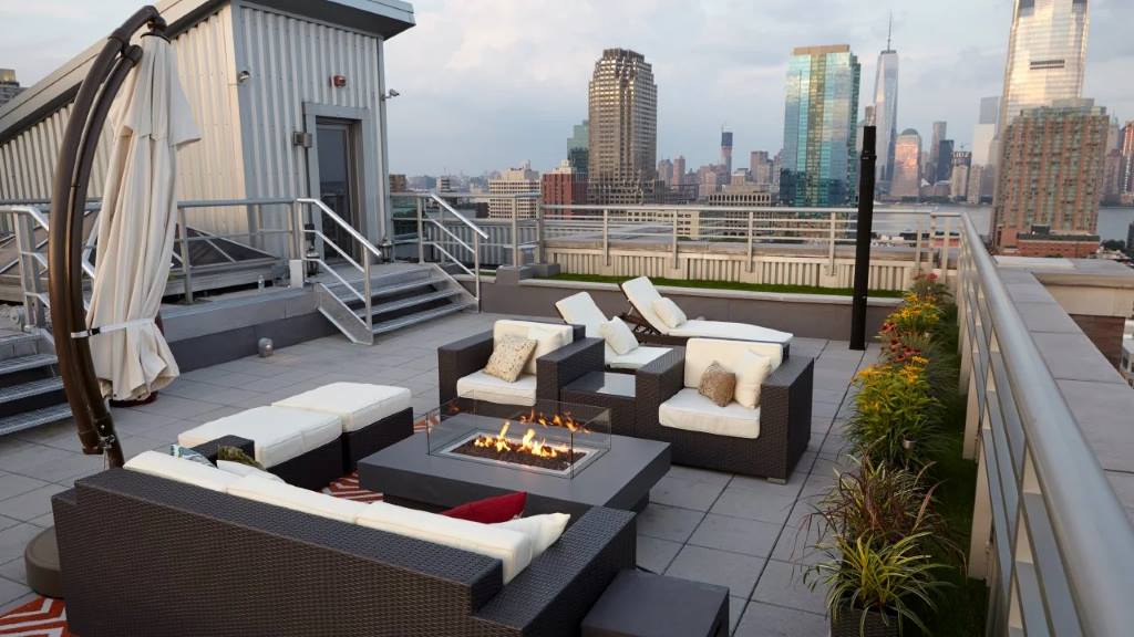 Finished rooftop deck with stone deck tiles and furniture under city skyline