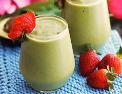 Colorful nutrient-packed green smoothie in glass with strawberry garnish beside Breville Fresh & Furious blender