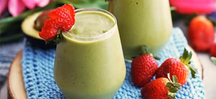 Colorful nutrient-packed green smoothie in glass with strawberry garnish beside Breville Fresh & Furious blender