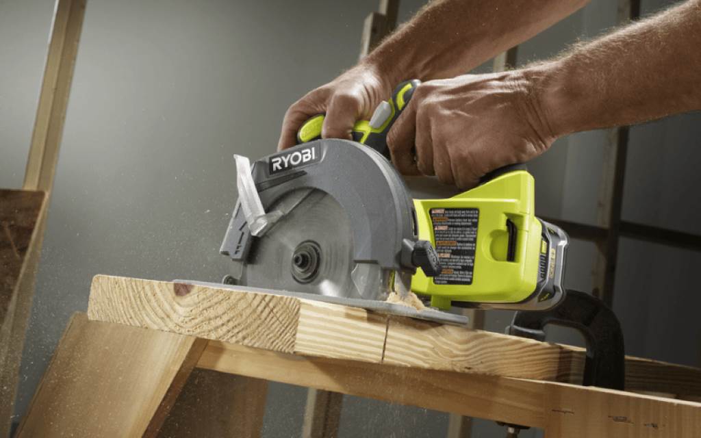 DIY user operating Ryobi P507 6 1 2 inch saw for framing, with dust extraction port connected to vacuum in garage setting