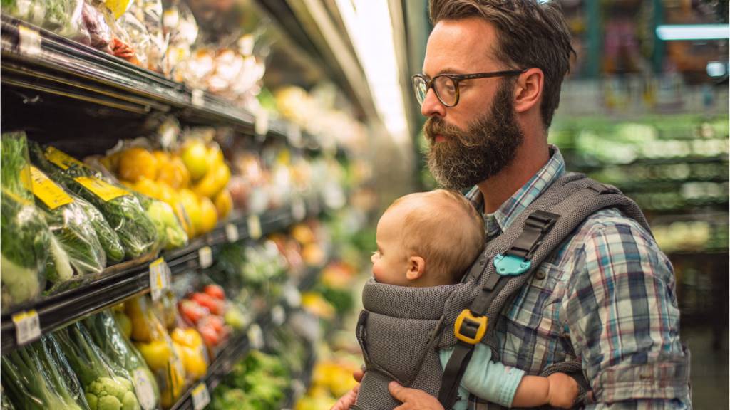 Dad grocery shopping hands-free using soft-structured baby carrier