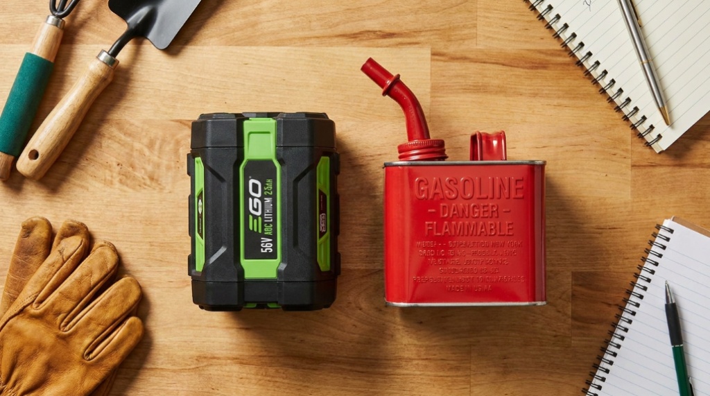 Cordless mower battery and gas container sitting together on a clean workbench